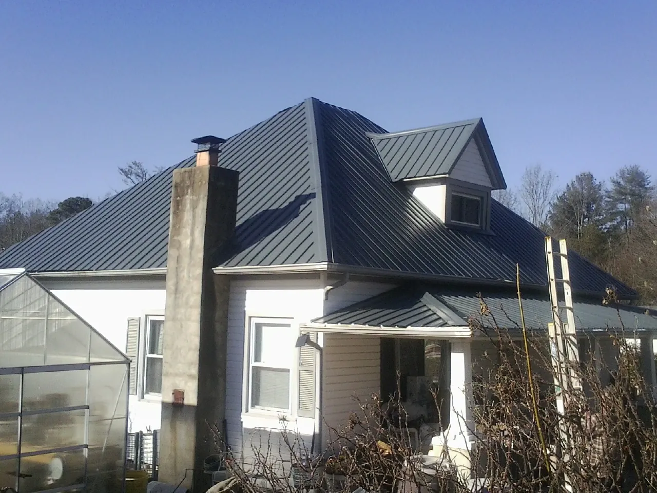 Dark blue standing seam metal roof on a white farmhouse with dormer — Slate & Tile Roof Repair by Roofing Brothers in Monmouth Junction