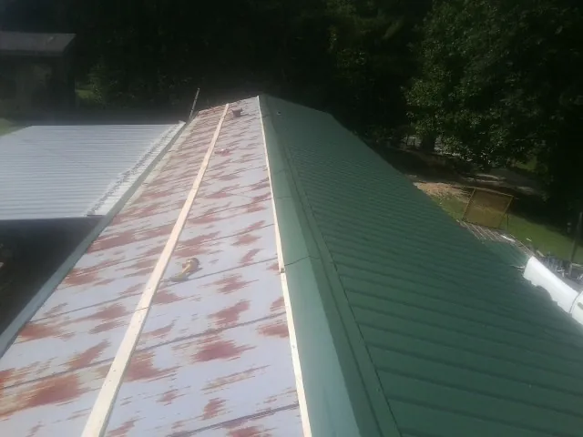 Old rusted panels beside newly installed green metal roofing — Wind Damage Roof Repair by Roofing Brothers in Monmouth Junction