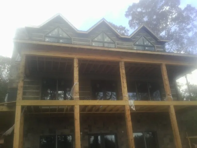Dormers and porch framing on a large log home under construction — Roof Coating work by our crew in Monmouth Junction