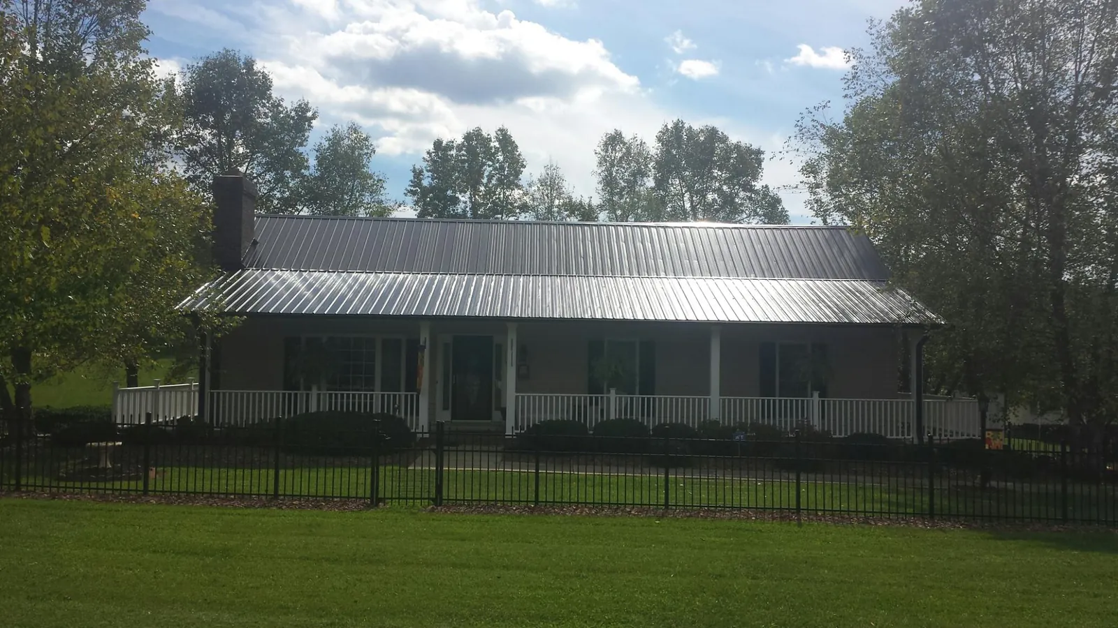 Gray metal roof on a brick ranch with a full width front porch — Gutter Guard Installation work by our crew in Monmouth Junction