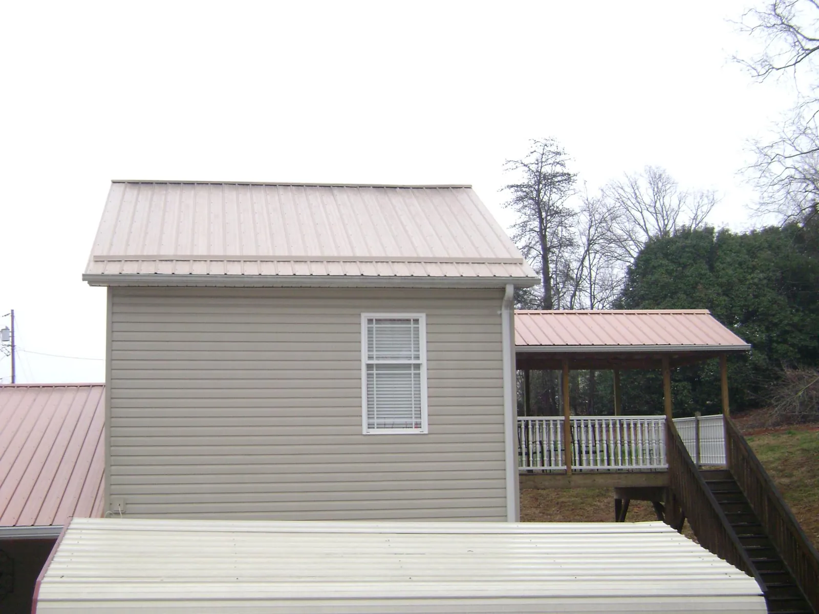 Tan metal roofs on a two story addition and attached porch, from a Roof Replacement job in Monmouth Junction