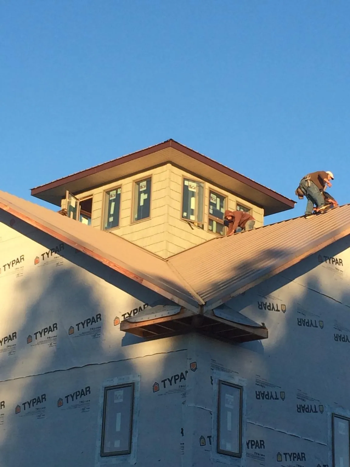 Roofers working around a rooftop cupola on a new metal roof at sunset — Roof Waterproofing in Monmouth Junction by Roofing Brothers